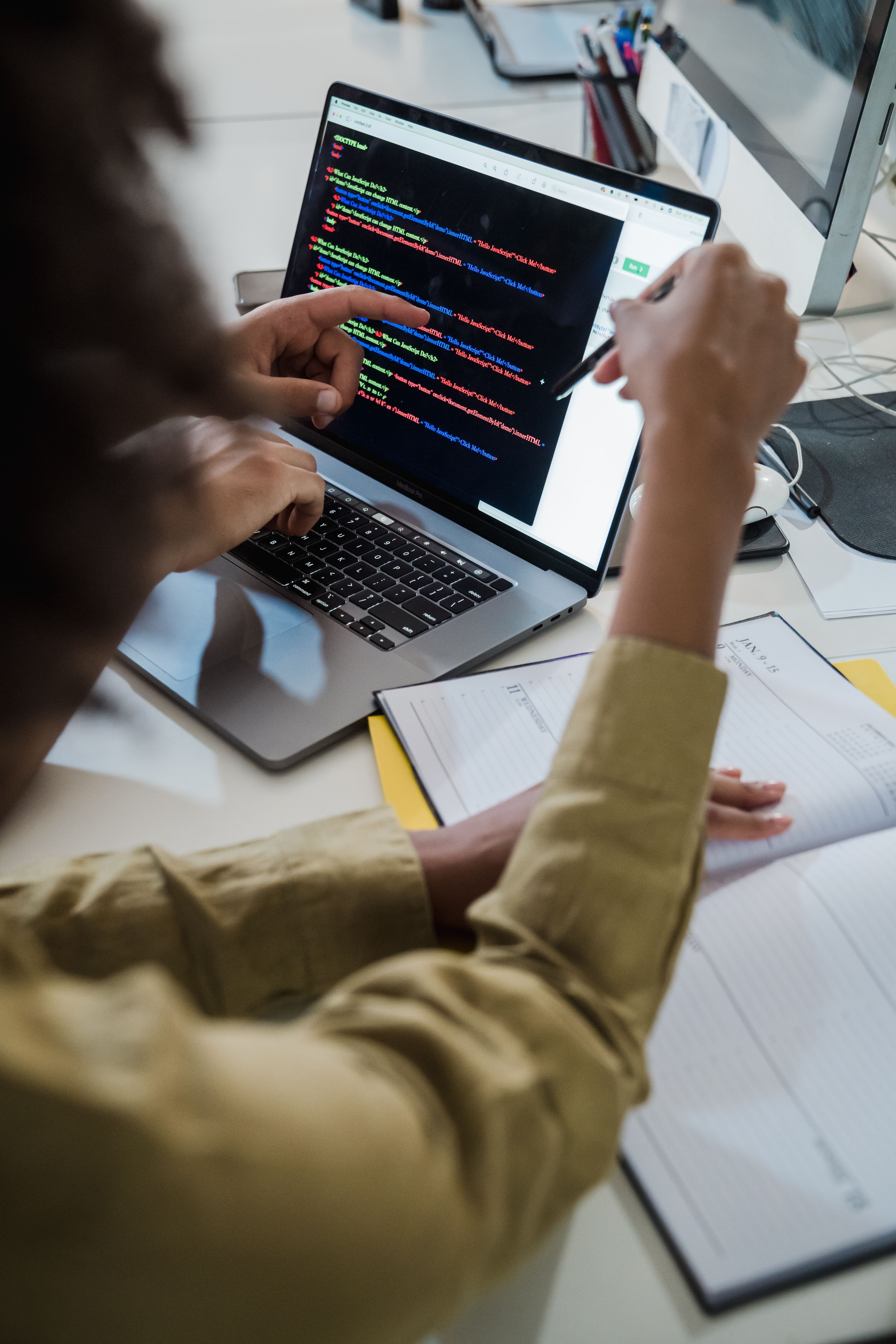 Two people reviewing software code together on a laptop